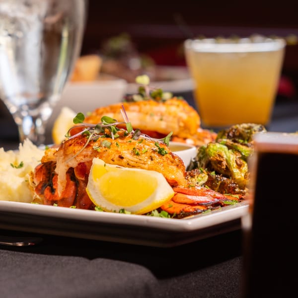 Laziza's American cuisine: lobster tails with mashed potatoes, roasted vegetables, and lemon.