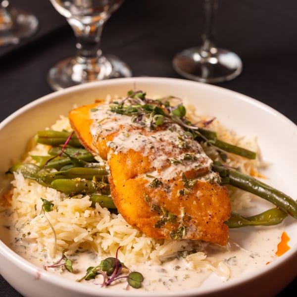 Laziza's American salmon dish with creamy sauce, green beans, and rice in a white bowl.
