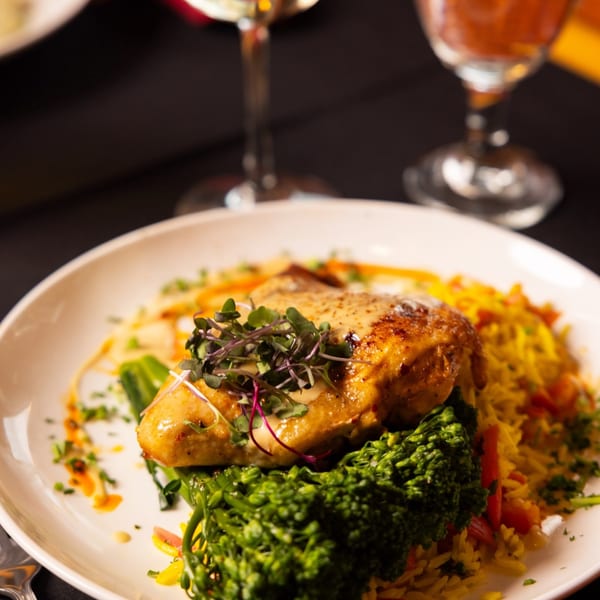 Laziza's American dish features chicken, broccoli, and rice, garnished with microgreens and sauce.